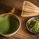 Bol de matcha vert vif fouetté en céramique artisanale avec poudre de matcha et chasen en bambou sur bois