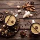 Deux tasses de chai latte avec épices — gingembre, cannelle, anis étoilé, cardamome et vanille sur fond de bois