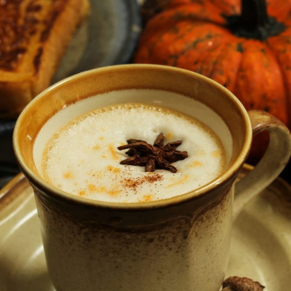 Tasse de chai latte citrouille épicée avec anis étoilé et cannelle, citrouilles en arrière-plan