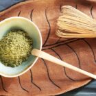 Poudre de matcha dans un bol avec chasen et cuillère sur plateau en forme de feuille