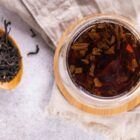 Tasse de verre avec infusion de thé noir Earl Grey cuivrée et feuilles de thé vrac