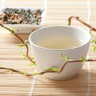 Tasse de thé vert genmaicha vert-doré avec mélange feuilles et riz soufflé en arrière-plan sur napperon bambou