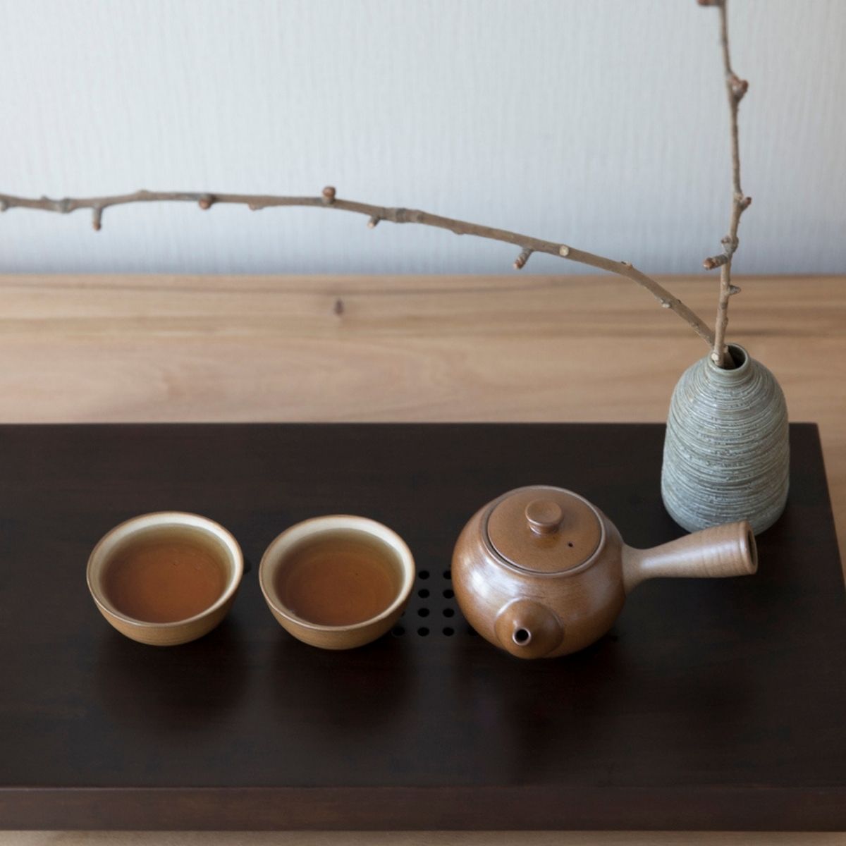 Deux tasses de thé vert sencha en céramique artisanale avec théière brune sur plateau noir ambiance zen japonaise